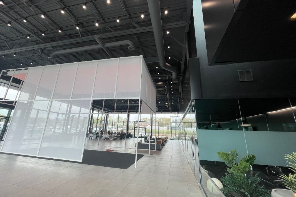 Interior of Genesis Braintree Car Dealership with modern sleep layout, tile floor, glass walls and interior garden feature