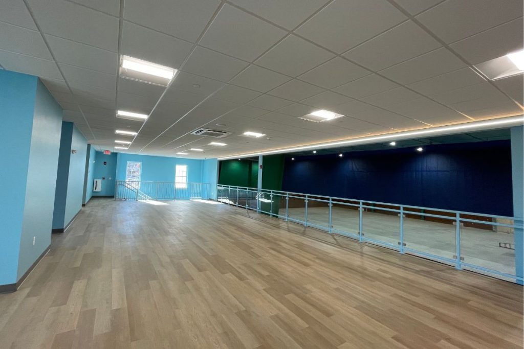 Viewing area at Badminton facility in Westborough with laminate flooring and vibrant colors on the walls.