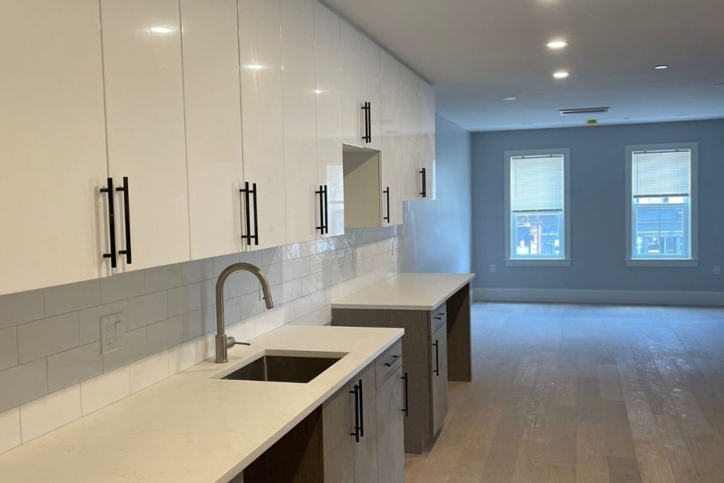 White and wood cabinets with white backsplash and white quartz countertops in South Boston Condo block