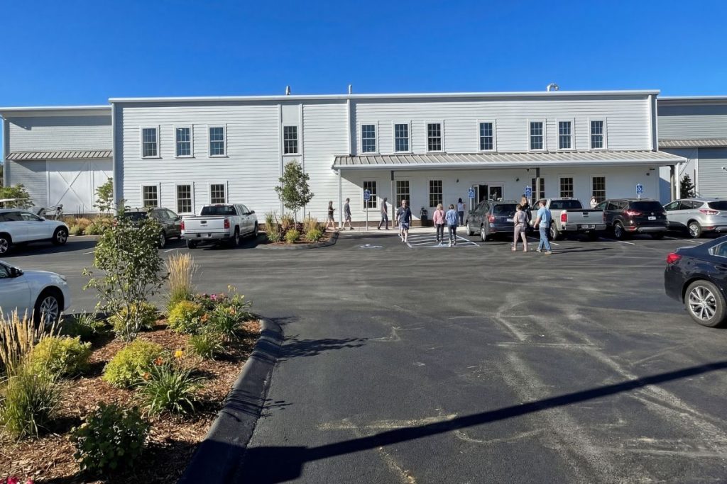 Realistic architectural rendering of the front of a badminton facility in Westborough, MA with people outside on a sunny day.