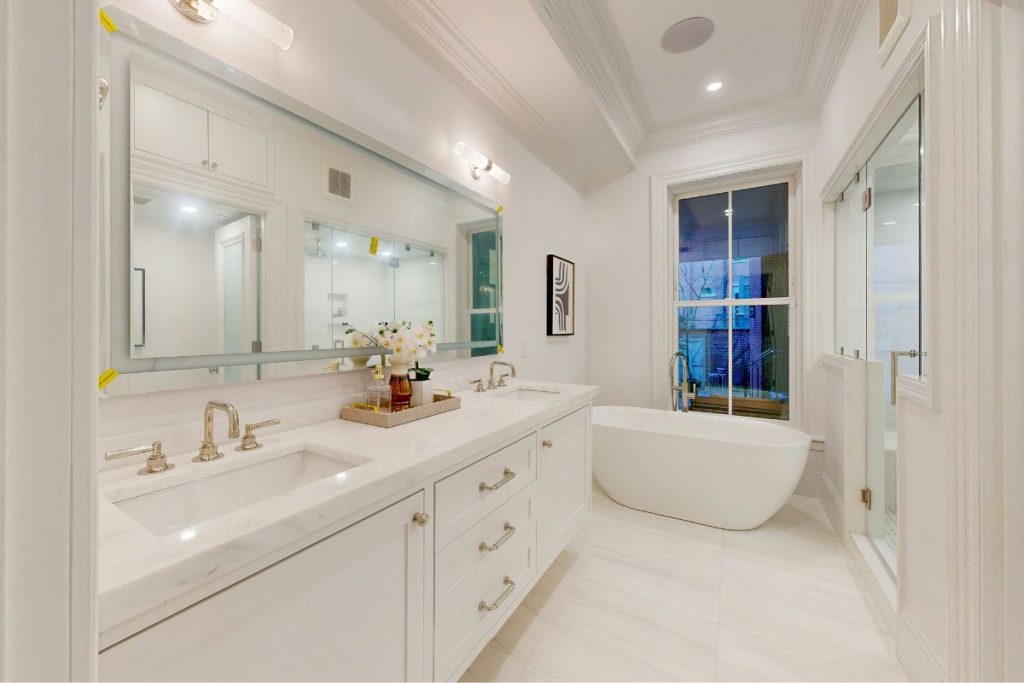 Master bathroom renovation with clean sleek countertop and tiles, white cabinets, bath and shower at a Beacon Hill Townhouse Boston Ma