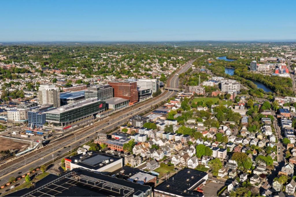Arial view of the Mass Pike west of the city of Boston, showing the New Balance Building opposite architect designed condo block