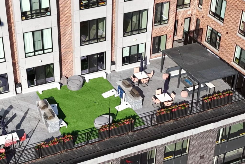 Green space on roof top with grills, seating, flower boxes, lighting at a luxury condo block in Quincy MA