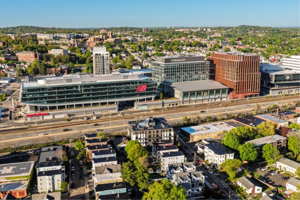 Arial photo of white and brown condo building in Brighton opposite the New Balance Building with the Mass Pike in between
